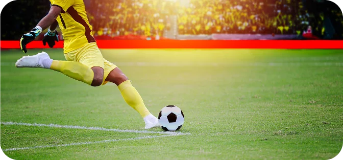 Un joueur de football vêtu d'un uniforme jaune s'apprête à frapper un ballon sur la ligne de corner d'un terrain vert